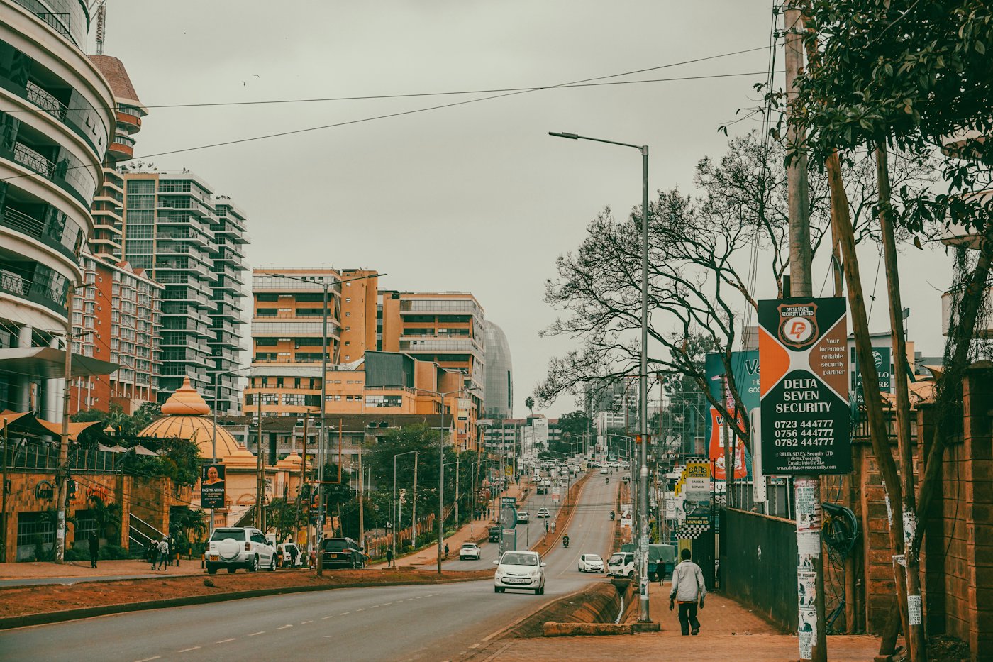 A man walking along a street lined with tall buildings